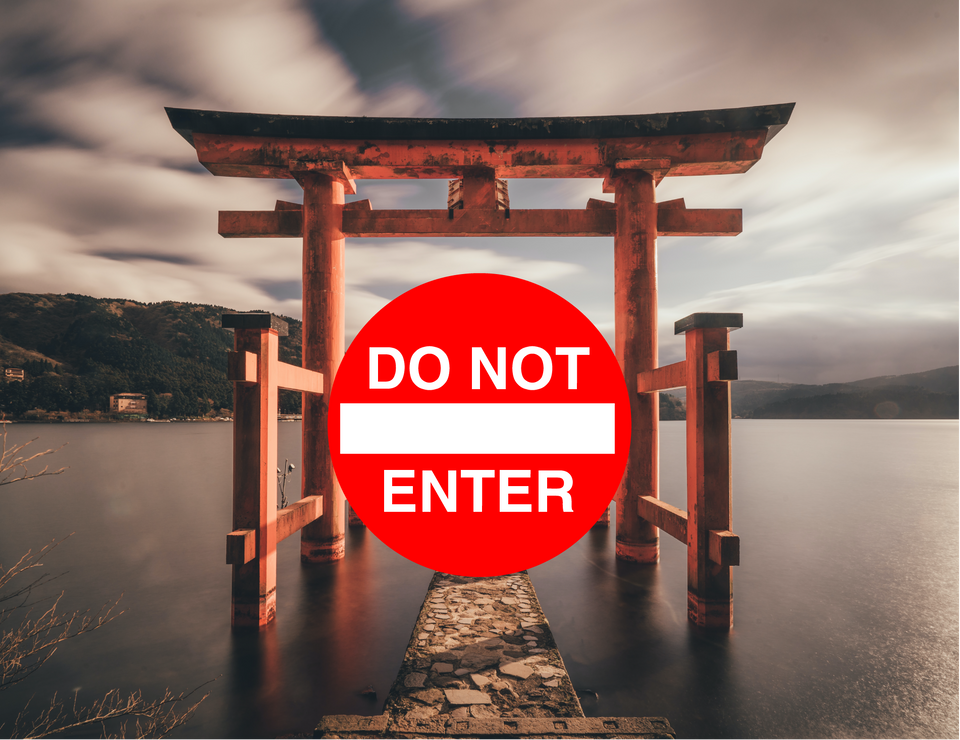 A Japanese shrine's torii with a "Do not enter sign" pasted across it.
